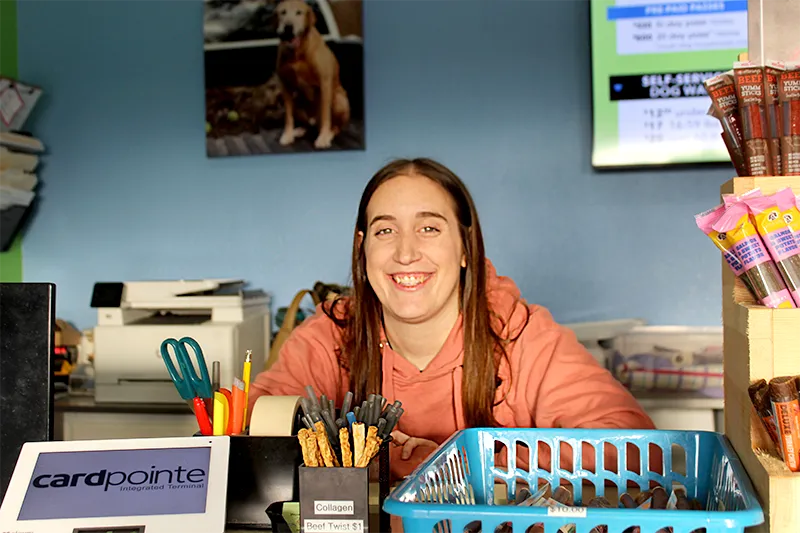 A Mud Puppies employee sitting at the front desk and smiling