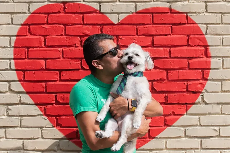 A Mud Puppies worker holds and kisses a small happy dog
